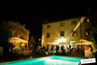 Bildet viser hage og basseng ved feriehuset Palazzo Pietro. Det er kveld og mørkt og hagen er fylt av bryllupsgjester. Huset ligger i Toscana mellom Pisa og Firenze.