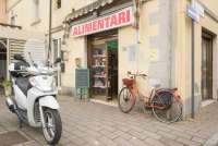 Bildet viser matbutikk med vespa utenfor i landsby nært Pisa i Italia.