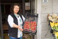 Bildet viser dame med jordbær utenfor matbutikk i landsby nært Pisa.