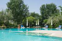 Bildet viser stort basseng i hagen til feriehus i landsby i Toscana.