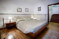 Bildet viser soverom med dobbeltseng i feriehus med stort basseng nært Pisa.