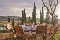 Bildet viser bord med toskansk mat på og utsikt på olivengård i Toscana.