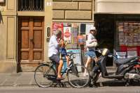 Mann og barn på sykkel. Barnet virker glad og løfter hendene i været og hilser på en dame som passerer. I nærområdet til ferieleiligheten Marco i sentrum av Firenze. Foto.