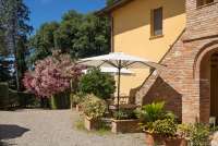 Staccia Buratta sin uteplass. Trapp opp til leiligheten bak. Bildet viser uteplass til feriehus på vingård med basseng i Toscana.