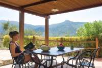 Bildet viser terrasse og dame som leser bok utenfor ferieboligen Villa Vista i Toscana.