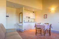 Bildet viser sofa, kjøkken og spisebord i ferieleilighet på vingård i Toscana.