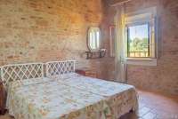 Bildet viser soverom med murvegg i feriehus på vingård i Toscana.