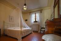 Bildet viser soverom med himmelseng i ferieleilighet på olivengård nært Pisa.