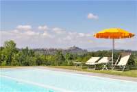 Bildet viser svømmebasseng og utsikt til middelalderlandsby i Toscana, midt mellom Pisa og Firenze